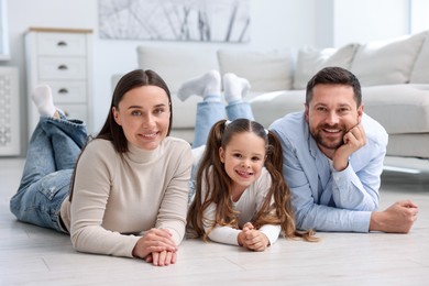 Photo of Parents and their daughter together on warm floor at home. Heating system