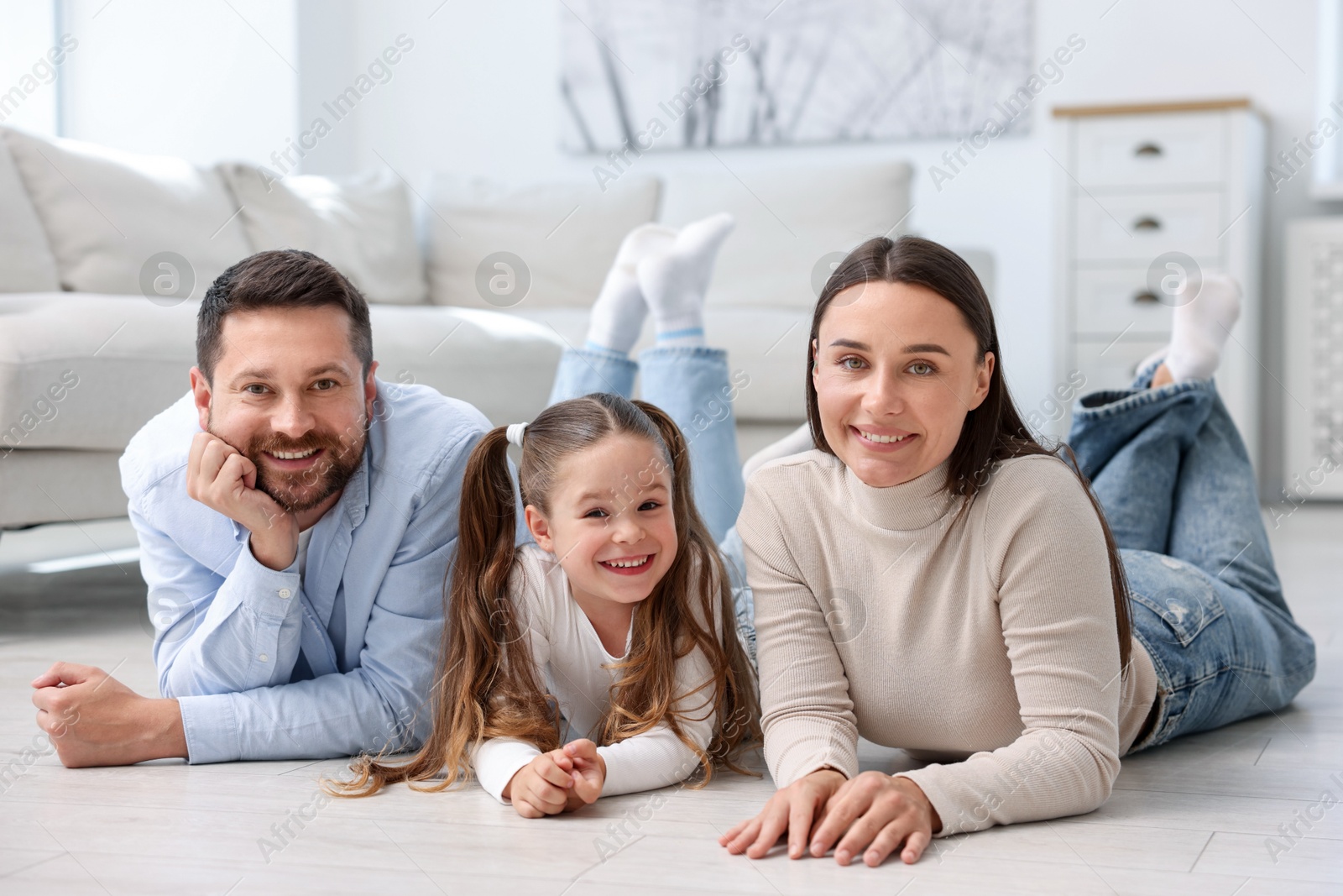 Photo of Parents and their daughter together on warm floor at home. Heating system
