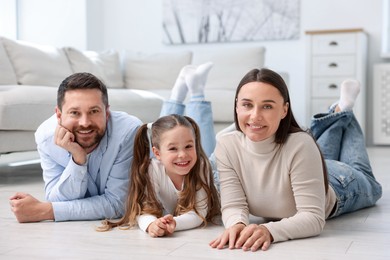 Photo of Parents and their daughter together on warm floor at home. Heating system