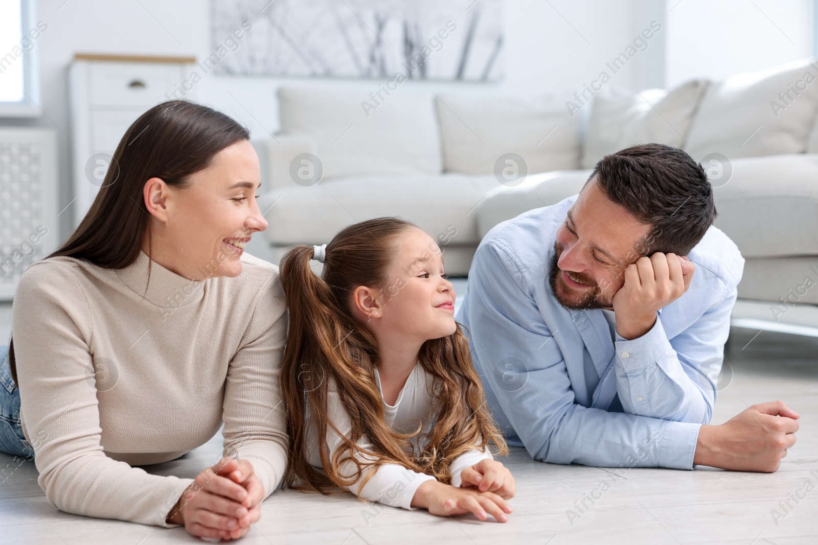 Photo of Parents and their daughter together on warm floor at home. Heating system