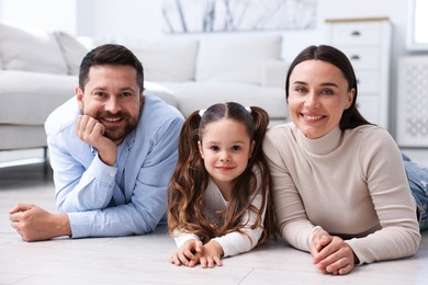 Photo of Parents and their daughter together on warm floor at home. Heating system