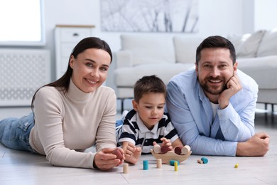 Photo of Parents and their son playing with toys on warm floor at home. Heating system