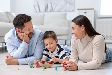 Photo of Parents and their son playing with toys on warm floor at home. Heating system