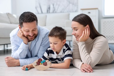 Photo of Parents and their son playing with toys on warm floor at home. Heating system