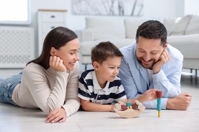 Photo of Parents and their son playing with toys on warm floor at home. Heating system