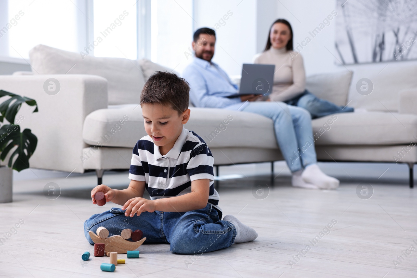 Photo of Boy playing with toys near his parents on warm floor at home, selective focus. Heating system