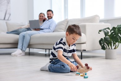 Photo of Boy playing with toys near his parents on warm floor at home, selective focus. Heating system
