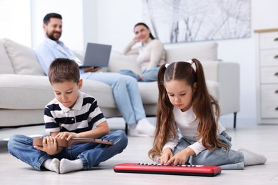 Photo of Kids playing with toys near their parents on warm floor at home, selective focus. Heating system
