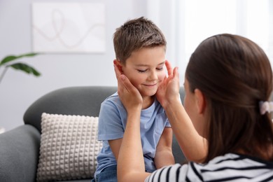 Photo of Mother supporting her sad son on sofa at home