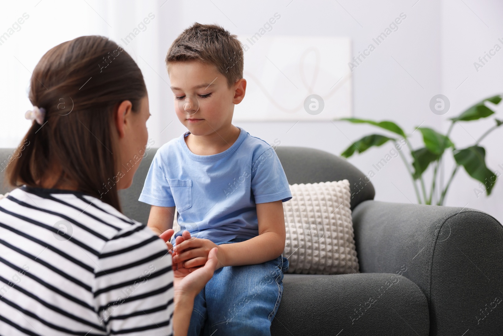 Mother supporting her sad son on sofa at home, space for text Photo of Mother supporting her sad son on sofa at home, space for text