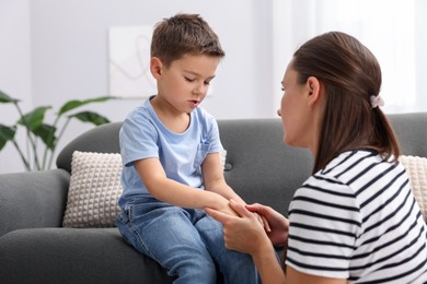 Photo of Mother supporting her sad son on sofa at home