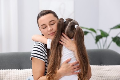 Photo of Mother supporting and hugging her sad daughter on sofa at home