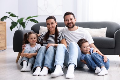 Photo of Parents and their kids together on warm floor at home. Heating system