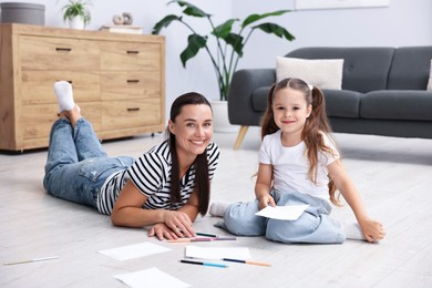 Photo of Mother and her daughter drawing together on warm floor at home. Heating system