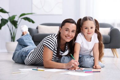 Photo of Mother and her daughter drawing together on warm floor at home. Heating system