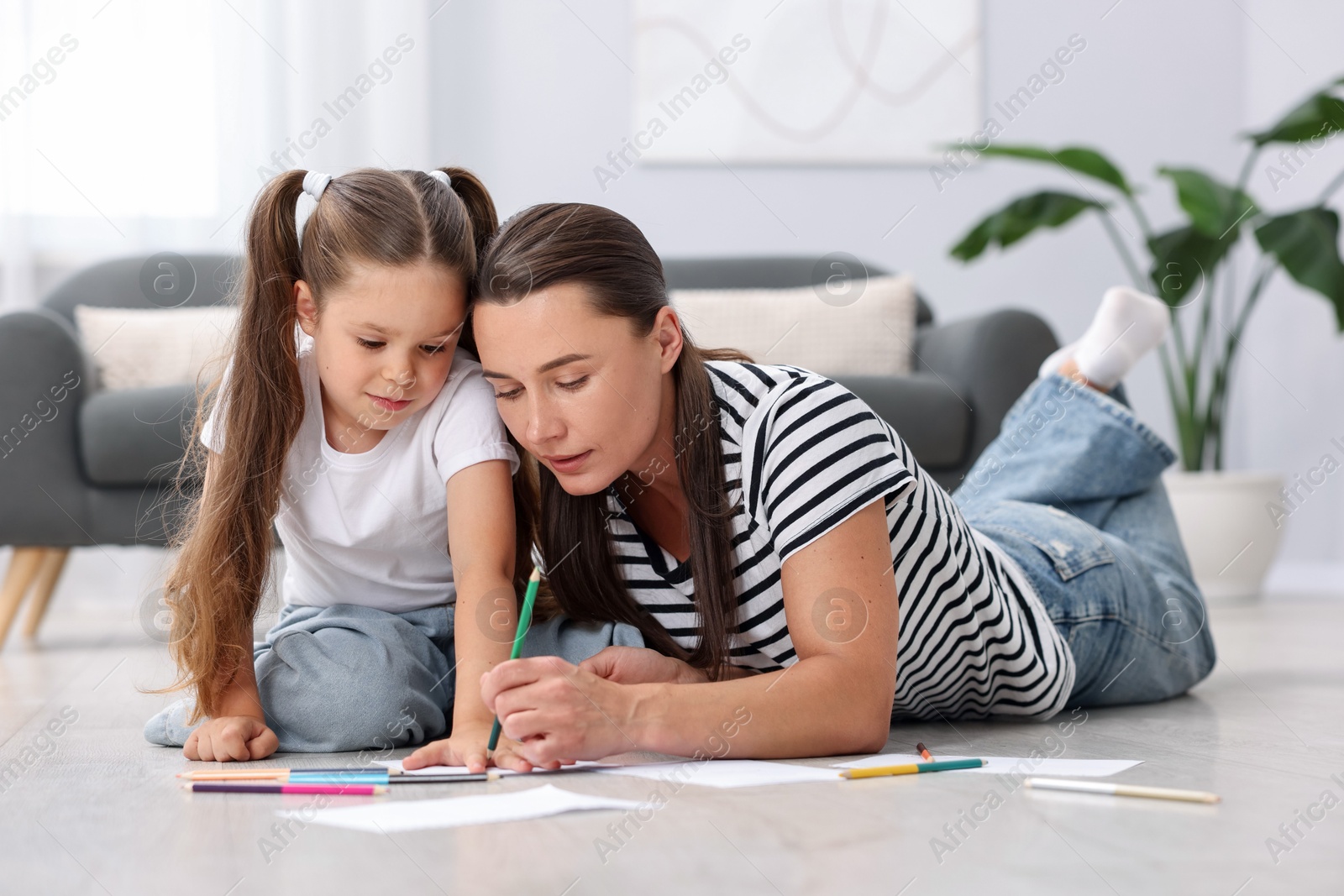 Photo of Mother and her daughter drawing together on warm floor at home. Heating system