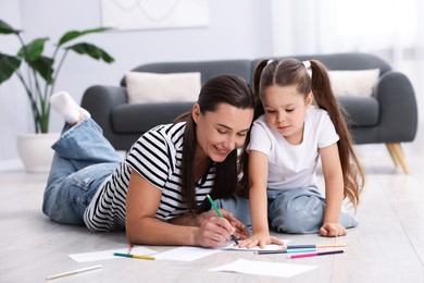 Photo of Mother and her daughter drawing together on warm floor at home. Heating system