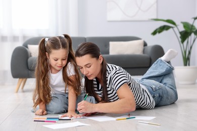 Photo of Mother and her daughter drawing together on warm floor at home. Heating system