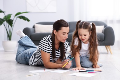 Photo of Mother and her daughter drawing together on warm floor at home. Heating system