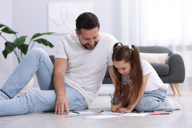 Photo of Father and his daughter drawing together on warm floor at home. Heating system