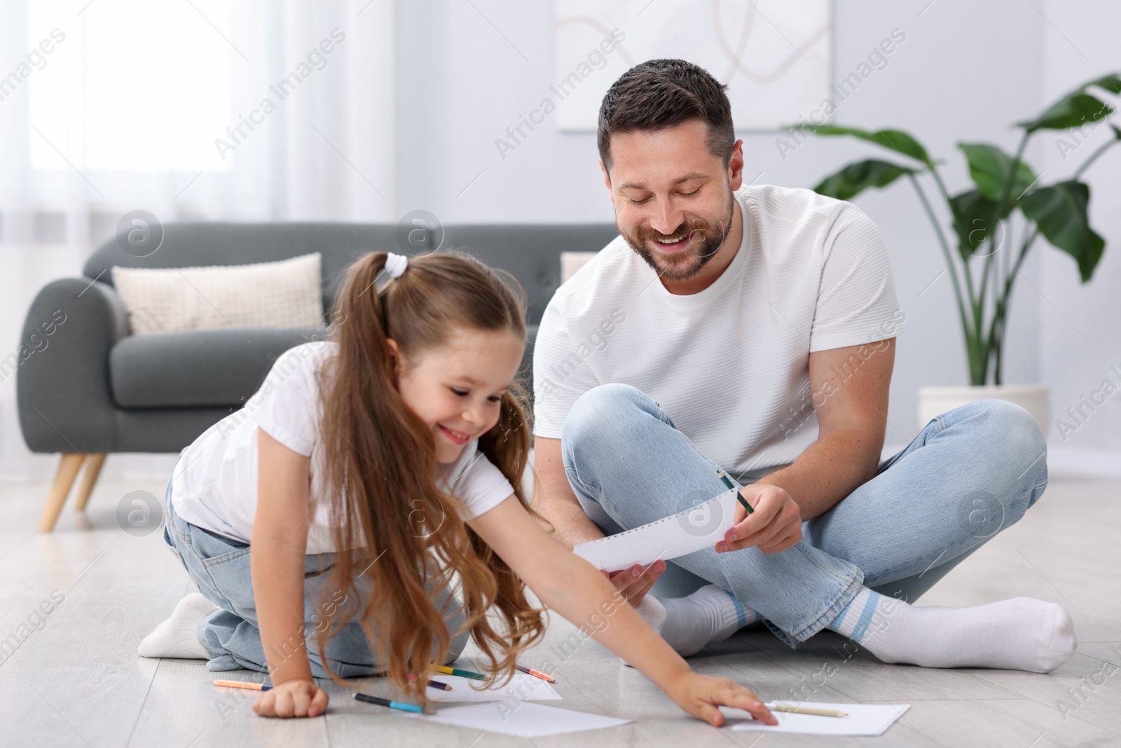 Photo of Father and his daughter drawing together on warm floor at home. Heating system