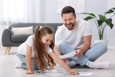Photo of Father and his daughter drawing together on warm floor at home. Heating system