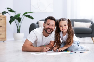 Photo of Father and his daughter drawing together on warm floor at home. Heating system