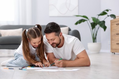 Photo of Father and his daughter drawing together on warm floor at home. Heating system