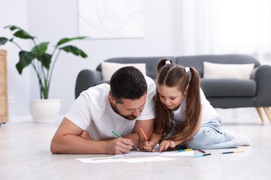 Photo of Father and his daughter drawing together on warm floor at home. Heating system