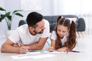 Photo of Father and his daughter drawing together on warm floor at home. Heating system