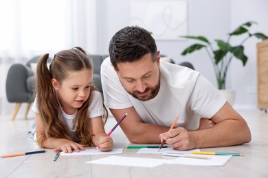 Photo of Father and his daughter drawing together on warm floor at home. Heating system