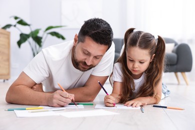 Photo of Father and his daughter drawing together on warm floor at home. Heating system