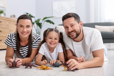 Photo of Parents and their daughter playing with toys on warm floor at home. Heating system