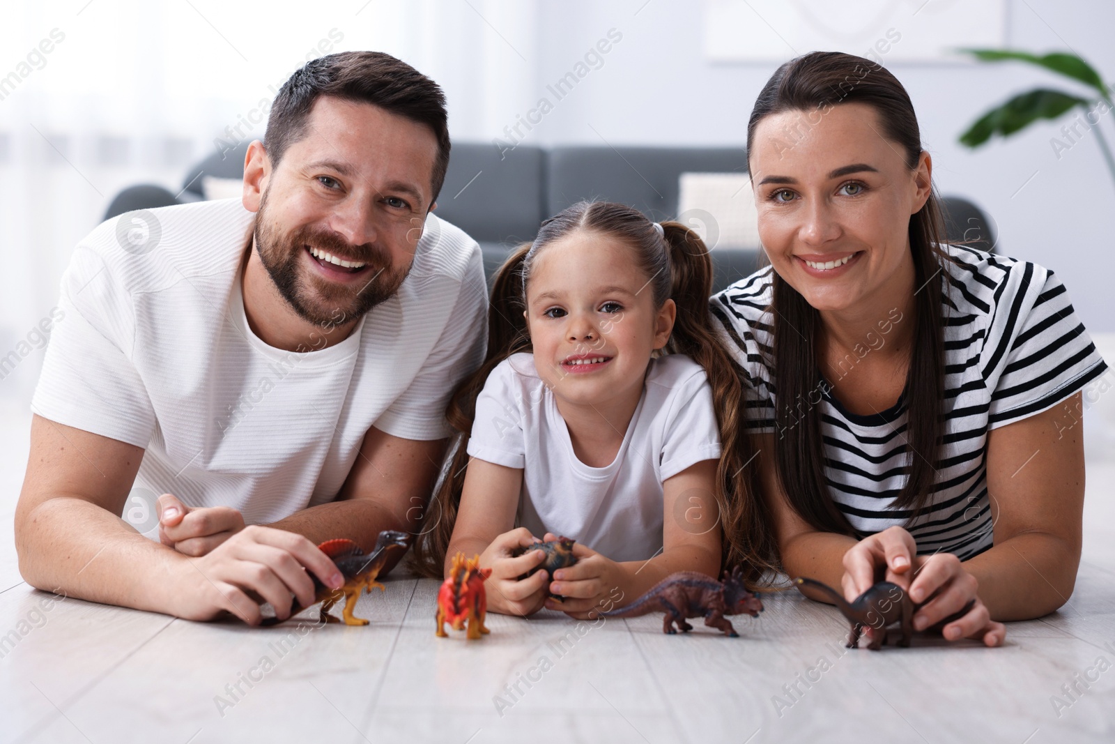 Parents and their daughter playing with toys on warm floor at home. Heating system Photo of Parents and their daughter playing with toys on warm floor at home. Heating system