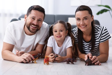 Photo of Parents and their daughter playing with toys on warm floor at home. Heating system