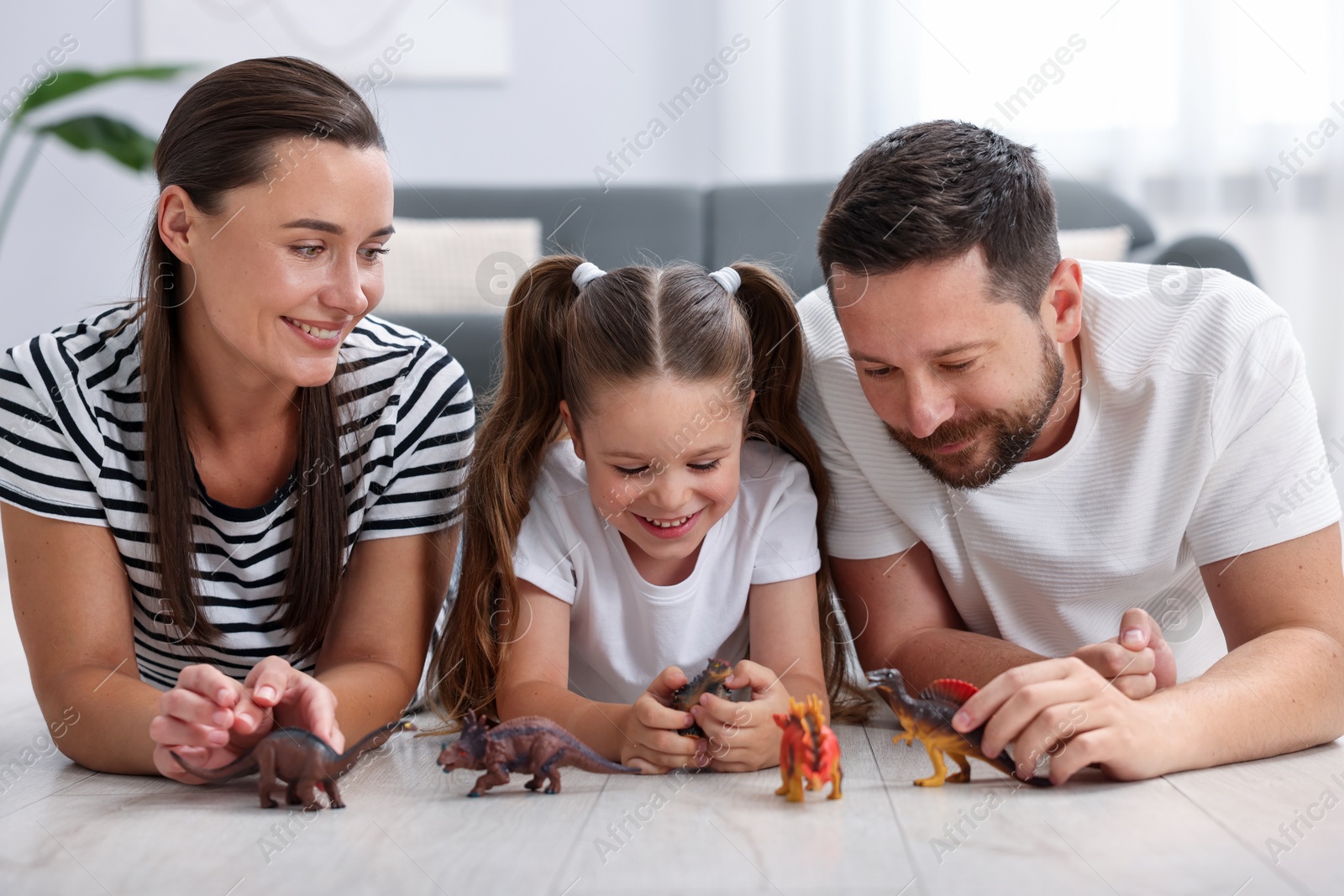 Parents and their daughter playing with toys on warm floor at home. Heating system Photo of Parents and their daughter playing with toys on warm floor at home. Heating system