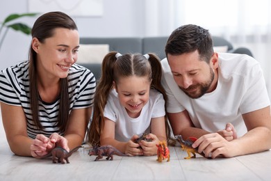 Photo of Parents and their daughter playing with toys on warm floor at home. Heating system