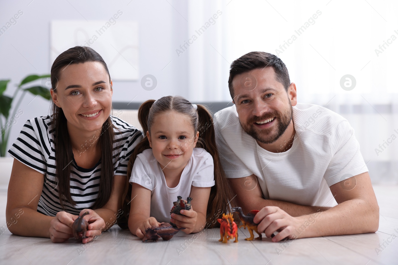 Parents and their daughter playing with toys on warm floor at home. Heating system Photo of Parents and their daughter playing with toys on warm floor at home. Heating system