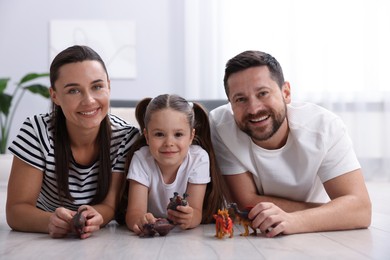 Photo of Parents and their daughter playing with toys on warm floor at home. Heating system