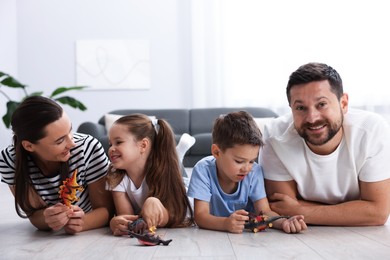 Photo of Parents and their kids playing with toys on warm floor at home. Heating system