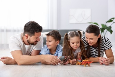 Photo of Parents and their kids playing with toys on warm floor at home. Heating system