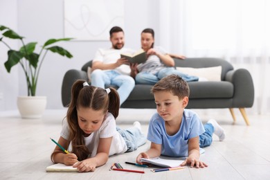 Photo of Kids drawing near their parents on warm floor at home, selective focus. Heating system