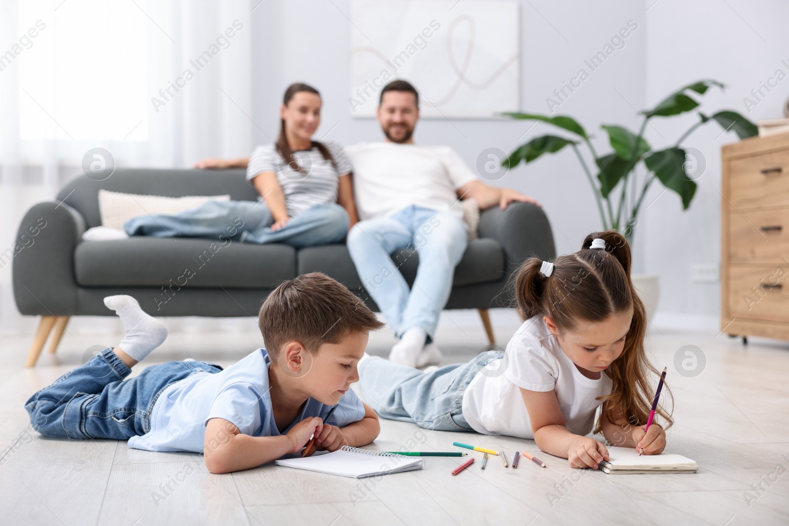 Kids drawing near their parents on warm floor at home, selective focus. Heating system Photo of Kids drawing near their parents on warm floor at home, selective focus. Heating system