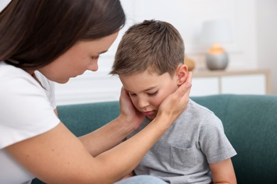 Photo of Mother supporting her sad son on sofa at home