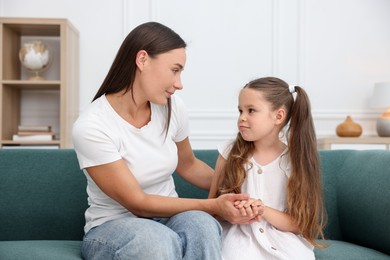 Photo of Mother supporting her sad daughter on sofa at home
