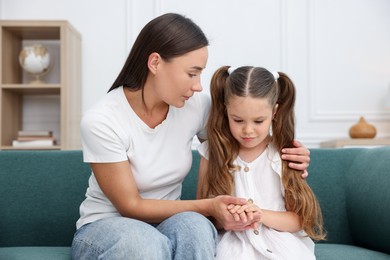 Photo of Mother supporting her sad daughter on sofa at home