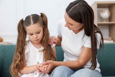 Photo of Mother supporting her sad daughter on sofa at home
