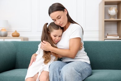 Photo of Mother supporting and hugging her sad daughter on sofa at home