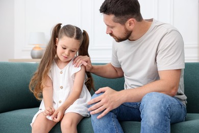 Photo of Father supporting his sad daughter on sofa at home