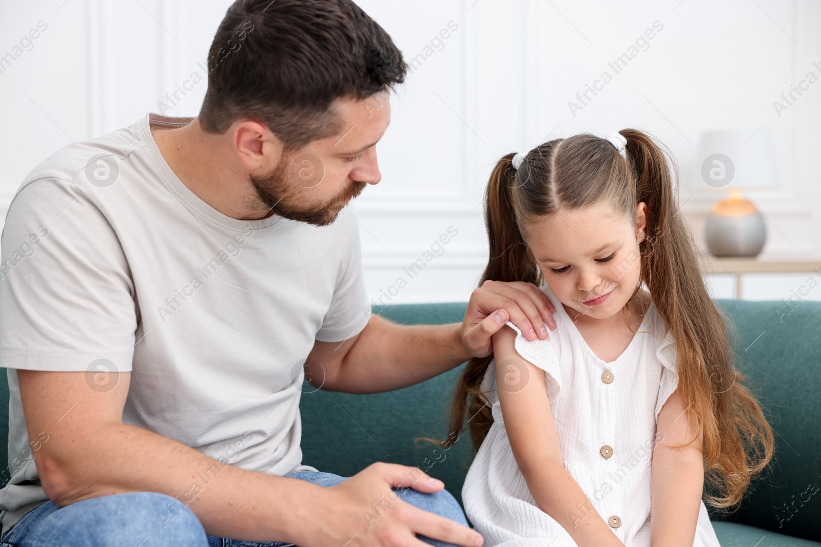 Father supporting his sad daughter on sofa at home Photo of Father supporting his sad daughter on sofa at home
